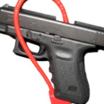 Imagem mostra uma Glock com um 'Gun Lock' passado na arma