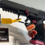 Mão segura uma pistola Taurus TX9 Competition, versão cano longo